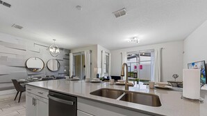 A modern kitchen with a central island, stainless steel sink, and a dishwasher. - Themed Home w/ Pool, Resort Perks & Prime Location (Kissimmee)