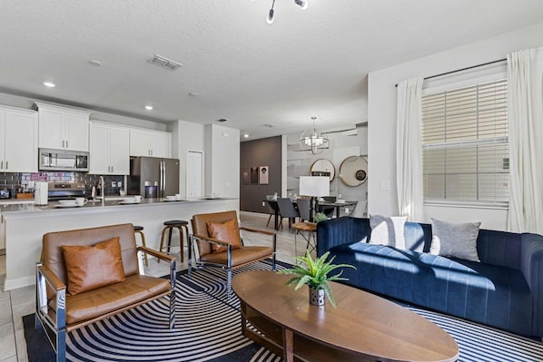 A modern living room with a blue sofa, two brown leather chairs, a wooden coffee table, and a patterned rug.