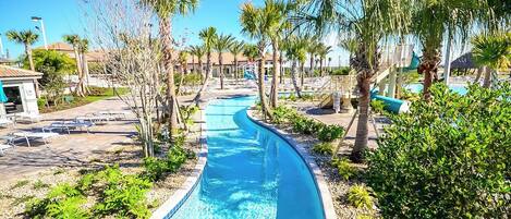 Ein Pool mit geschwungener Form, umgeben von Palmen und Liegestühlen.