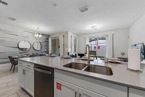 Une cuisine moderne dotée d’un îlot central, d’un évier en acier inoxydable et d’un lave-vaisselle.