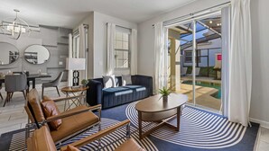 A modern living room with a sofa, armchairs, a coffee table, and a dining area. - Themed Home w/ Pool, Resort Perks & Prime Location (Kissimmee)
