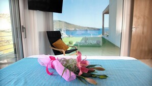 A hotel room with a bed, a chair, and a view of the sea. - Beachfront Villa Kyma. Your own paradise (Faistos)