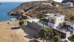 A coastal property with a modern house, a beach, and rocky terrain. - Beachfront Villa Kyma. Your own paradise (Faistos)