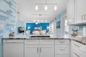 Kitchen features white cabinetry, gold handles, and a dishwasher.
