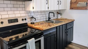 Una cucina con mobili bianchi, un piano cottura nero e un piano di lavoro in legno.