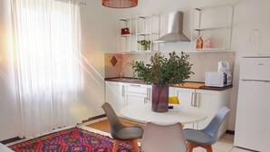 A compact living space with a kitchen area, a dining table with chairs, and a colorful rug. - Spacious apartment in historic country residence, between Perugia and Assisi (Perugia)