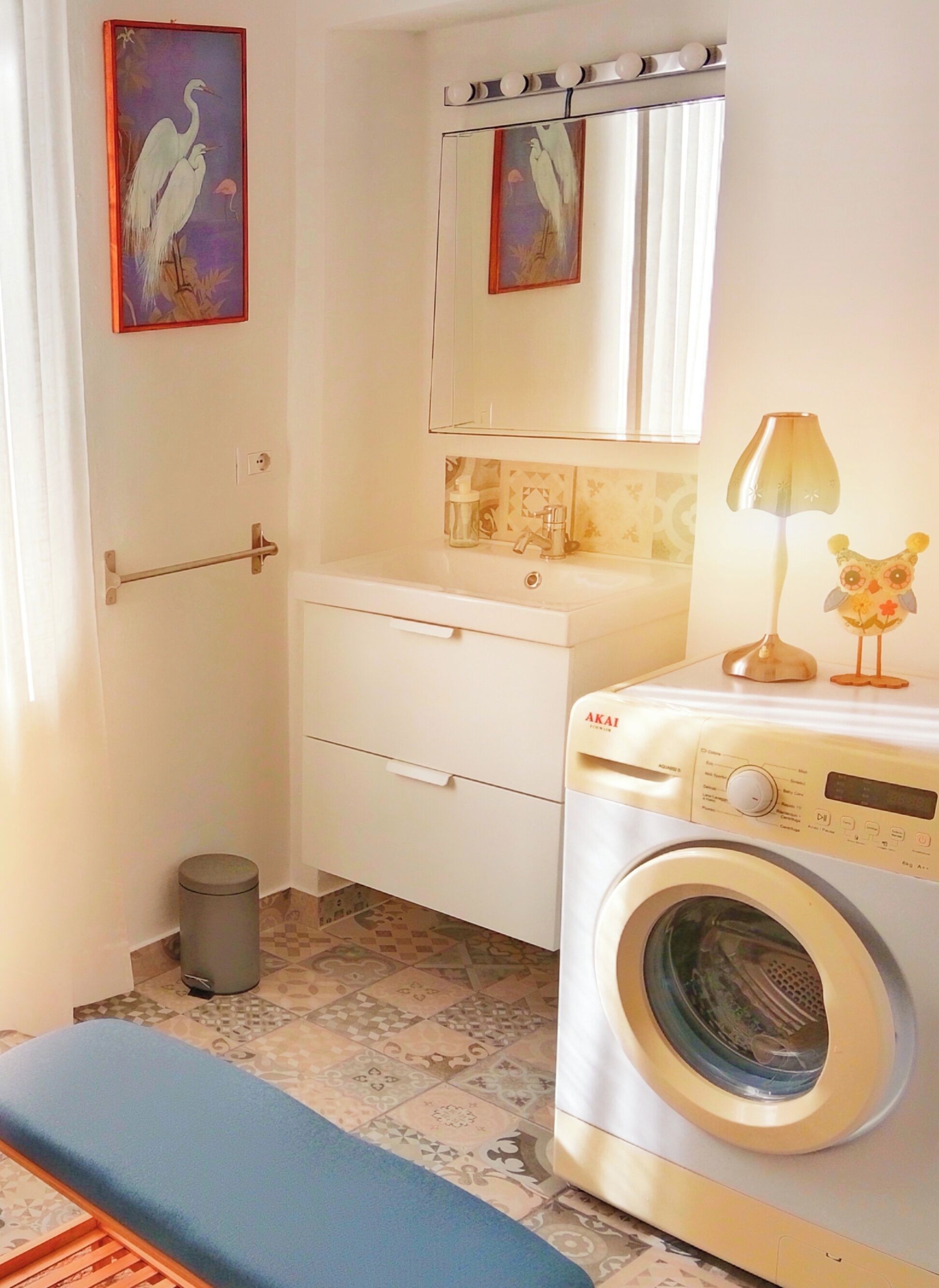 A compact bathroom with a washing machine, a sink, a mirror, and a toilet.