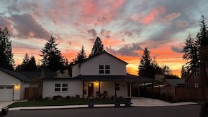 A residential house with a front porch, a driveway, and a street view.