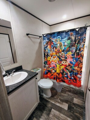 A bathroom with a white sink, toilet, and a shower curtain featuring cartoon characters.