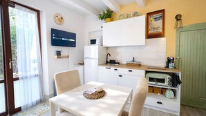 Una cocina moderna con armarios blancos, microondas integrado y una puerta verde.