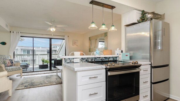 A modern kitchen with a central island, stainless steel appliances, and pendant lighting. - Pet Friendly 1 BR Condo with a View! (Carolina Beach)