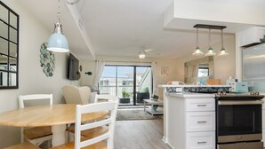 A modern kitchen with white cabinetry, a stainless steel oven, and pendant lighting. - Pet Friendly 1 BR Condo with a View! (Carolina Beach)
