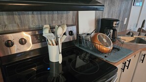 A kitchen with a black stove, a coffee maker, and various utensils in a holder.