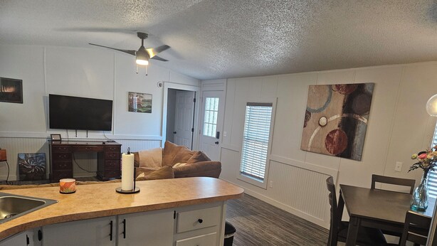 A compact kitchen with a central island, a dining area with a table and chairs, and a living space with a sofa.
