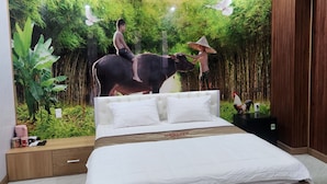 Ein Schlafzimmer mit einem großen Bett, einem Holz-Kopfteil, einem Nachttisch und einer Wandmalerei mit einer Waldszene, die eine Kuh und eine Person zeigt.