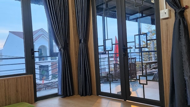 Ein Zimmer mit großem Fenster, Holzboden und einer grünen Bank.