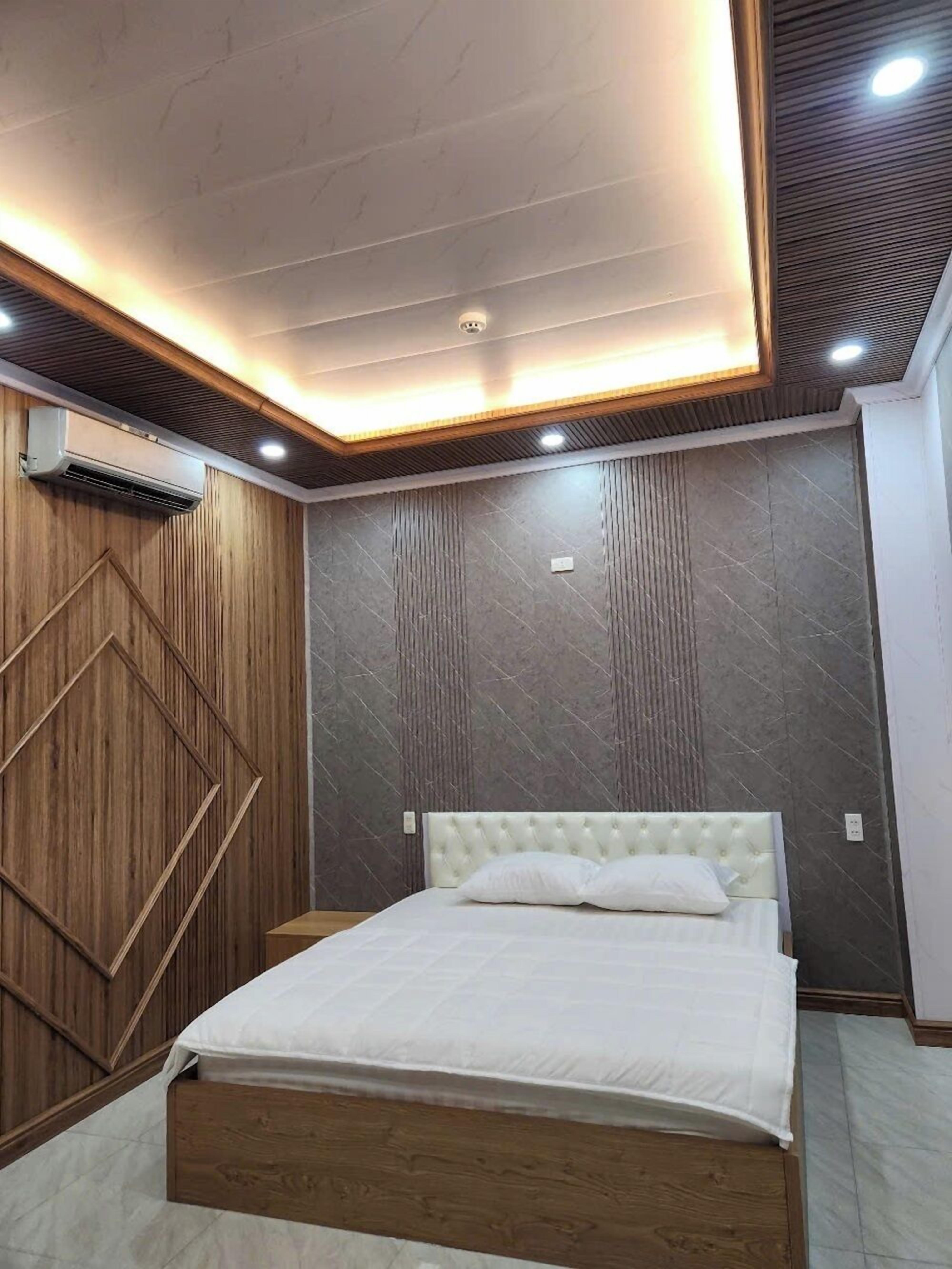 Un dormitorio con cama, paneles de madera y un diseño moderno en el techo.