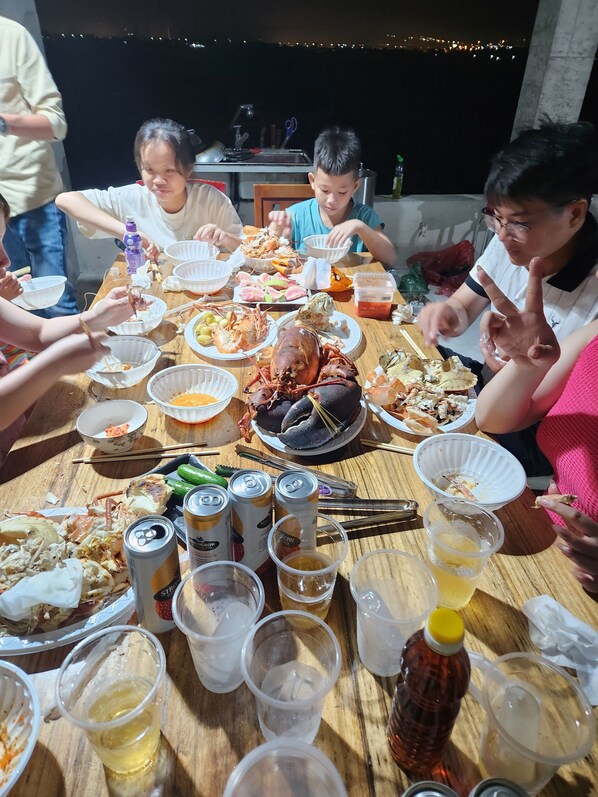 A group of people dining at a table with various dishes, drinks, and utensils. - Newlife Homestay (Ham Thang)
