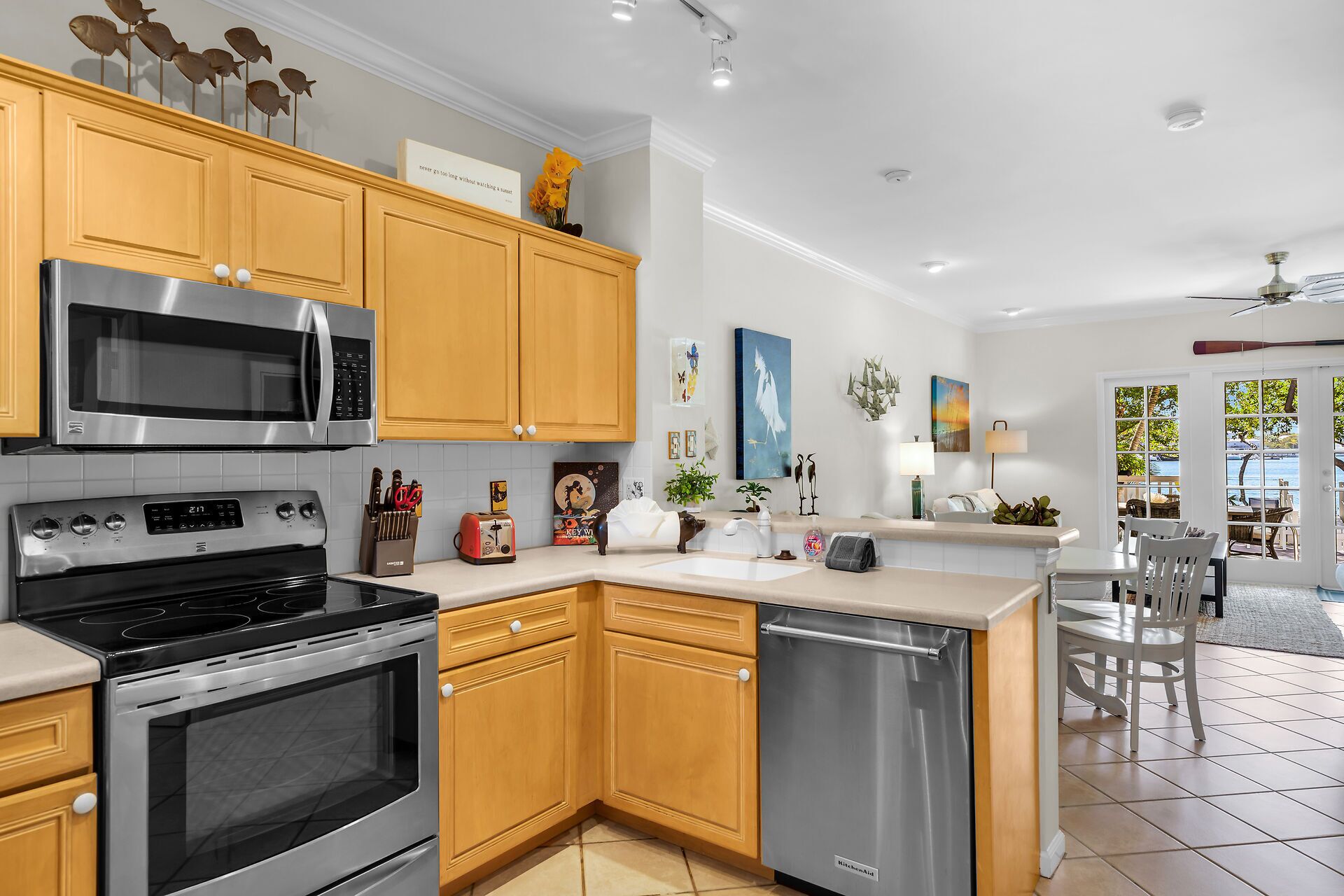 A modern kitchen with stainless steel appliances, wooden cabinets, and a view of the outdoors.