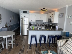 Una cocina moderna con una isla central, armarios blancos y un refrigerador de acero inoxidable.