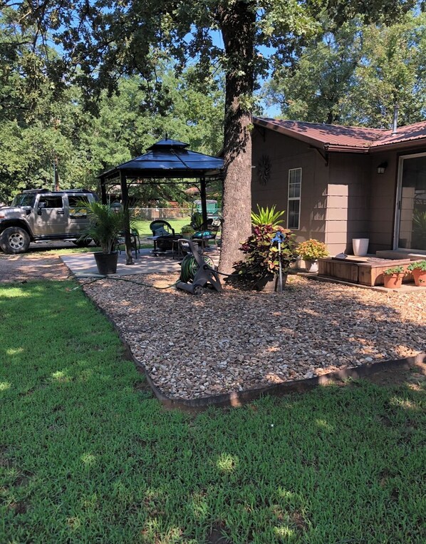 A patio area with a gazebo, a tree, and a vehicle parked nearby.