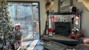 A cozy living room with a fireplace, a Christmas tree, and deer antlers on the wall.