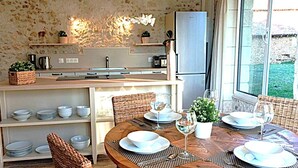 A dining area with a wooden table set for two, surrounded by wicker chairs. - Cottage Brantôme Swimming pool Tennis Castle Monciaux (Bourrou)