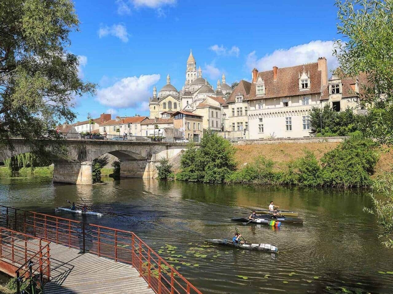 A river with boats, a bridge, and historic buildings in the background.