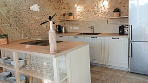 A kitchen with white cabinets, a stainless steel refrigerator, a wooden countertop, and a stone wall. - Cottage Brantôme Swimming pool Tennis Castle Monciaux (Bourrou)