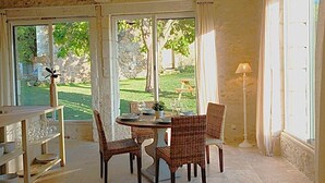 A dining area with wicker chairs, a round table, and a view of a garden through large windows. - Cottage Brantôme Swimming pool Tennis Castle Monciaux (Bourrou)