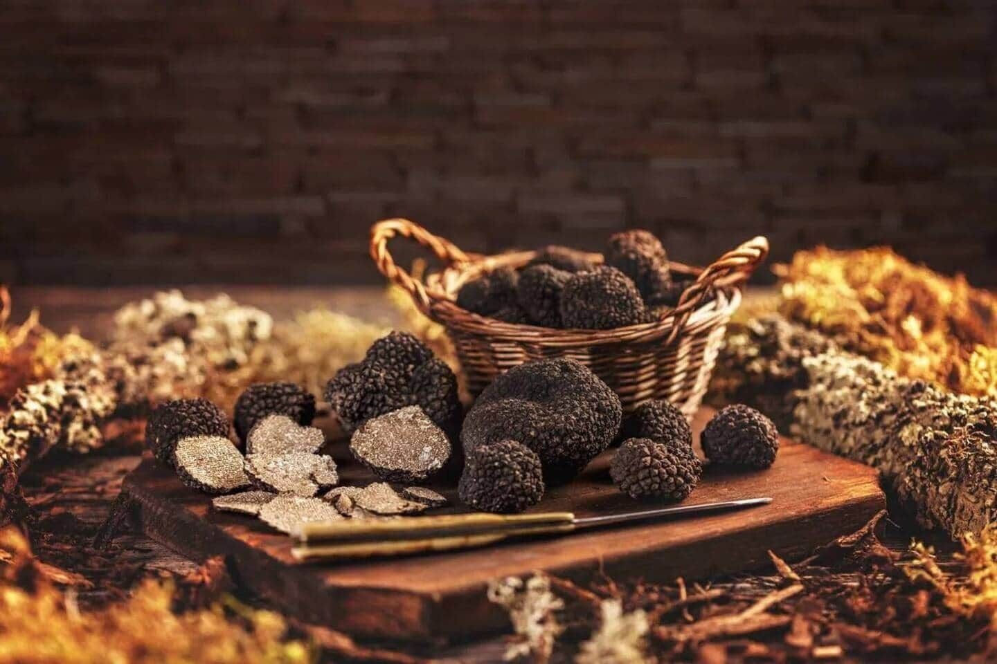 A basket of black truffles on a wooden surface with a rustic background.
