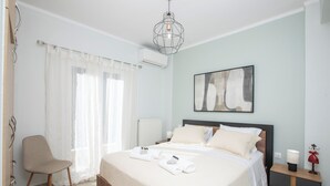 A neatly arranged bedroom with a bed, a chair, a bedside table, and a wall-mounted artwork.