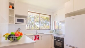 A modern kitchen with white cabinetry, a microwave, a toaster, and a fruit bowl on the counter. - Amanda Court 14, 1-5 Weatherly Close - 250 metres from Shoal Bay Beach (Nelson Bay)