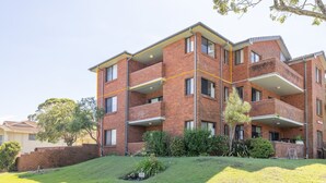 A multi-story brick building with balconies, a grassy front yard, and a clear sky. - Amanda Court 14, 1-5 Weatherly Close - 250 metres from Shoal Bay Beach (Nelson Bay)