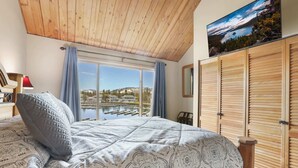Ein Schlafzimmer mit einem großen Bett, Blick auf einen Yachthafen und Holzhörner.
