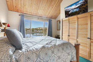 Un dormitorio con una cama grande, vista a un puerto deportivo y persianas de madera.