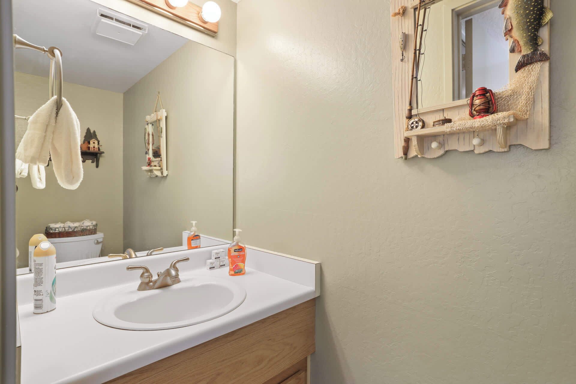 A bathroom with a white sink, a mirror, and a towel hanging on a rack.