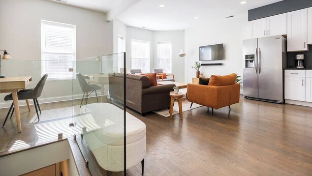 A modern apartment with a living room, dining area, kitchen, and a glass partition separating the living and dining spaces. - Bright & Modern Apt | Steps to Lake, Train, Food (Chicago)