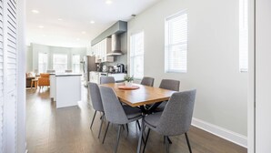 A modern kitchen with a central island, a dining area with a wooden table and grey chairs, and a living area with a sofa and a coffee table. - Bright & Modern Apt | Steps to Lake, Train, Food (Chicago)