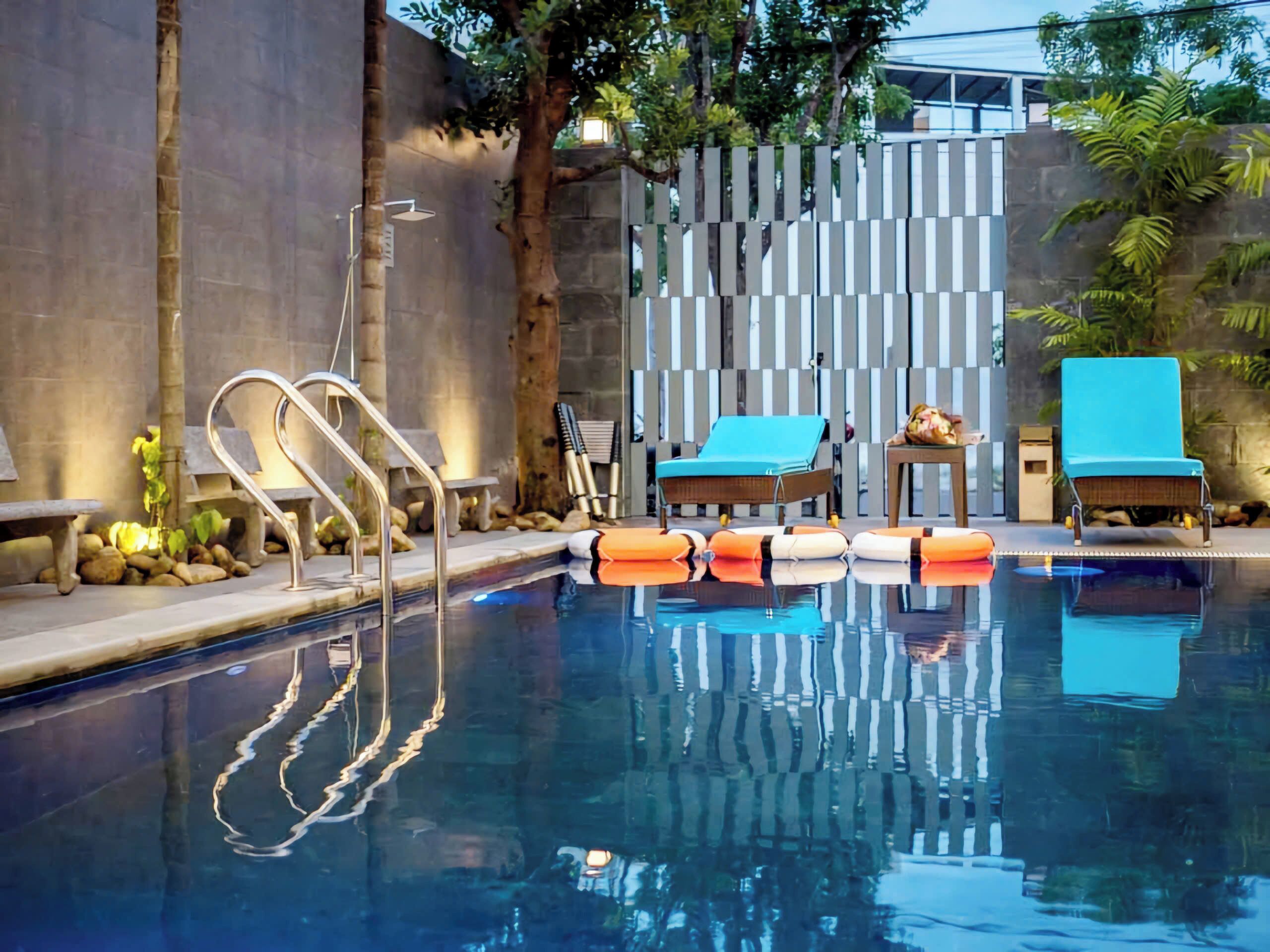 A swimming pool with lounge chairs and a stone wall.