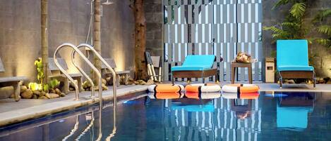 A swimming pool with lounge chairs and a stone wall.