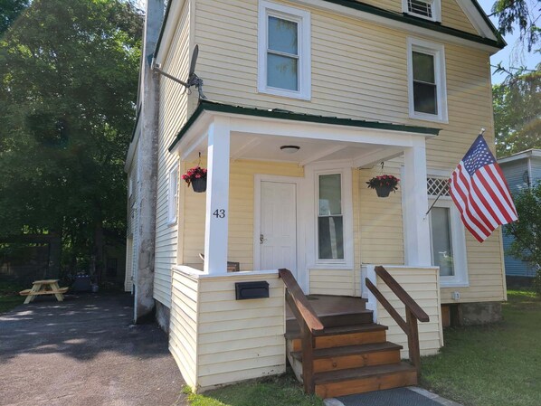 A two-story house with a front porch, a mailbox, and an American flag.