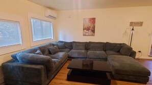 Ein Wohnzimmer mit einem Ecksofa, einem Couchtisch und einem Gemälde an der Wand.