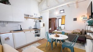 Un espace de vie compact comprenant une kitchenette, un coin repas et une chambre.