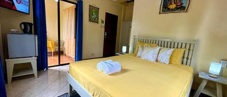 A hotel room with a bed, a desk, a television, and a door leading to a balcony.