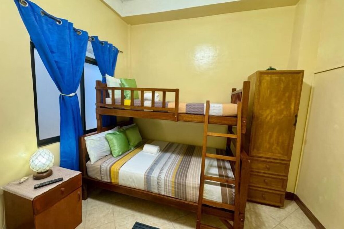 A bunk bed with a wooden ladder, a bedside table with a lamp, and a wardrobe.