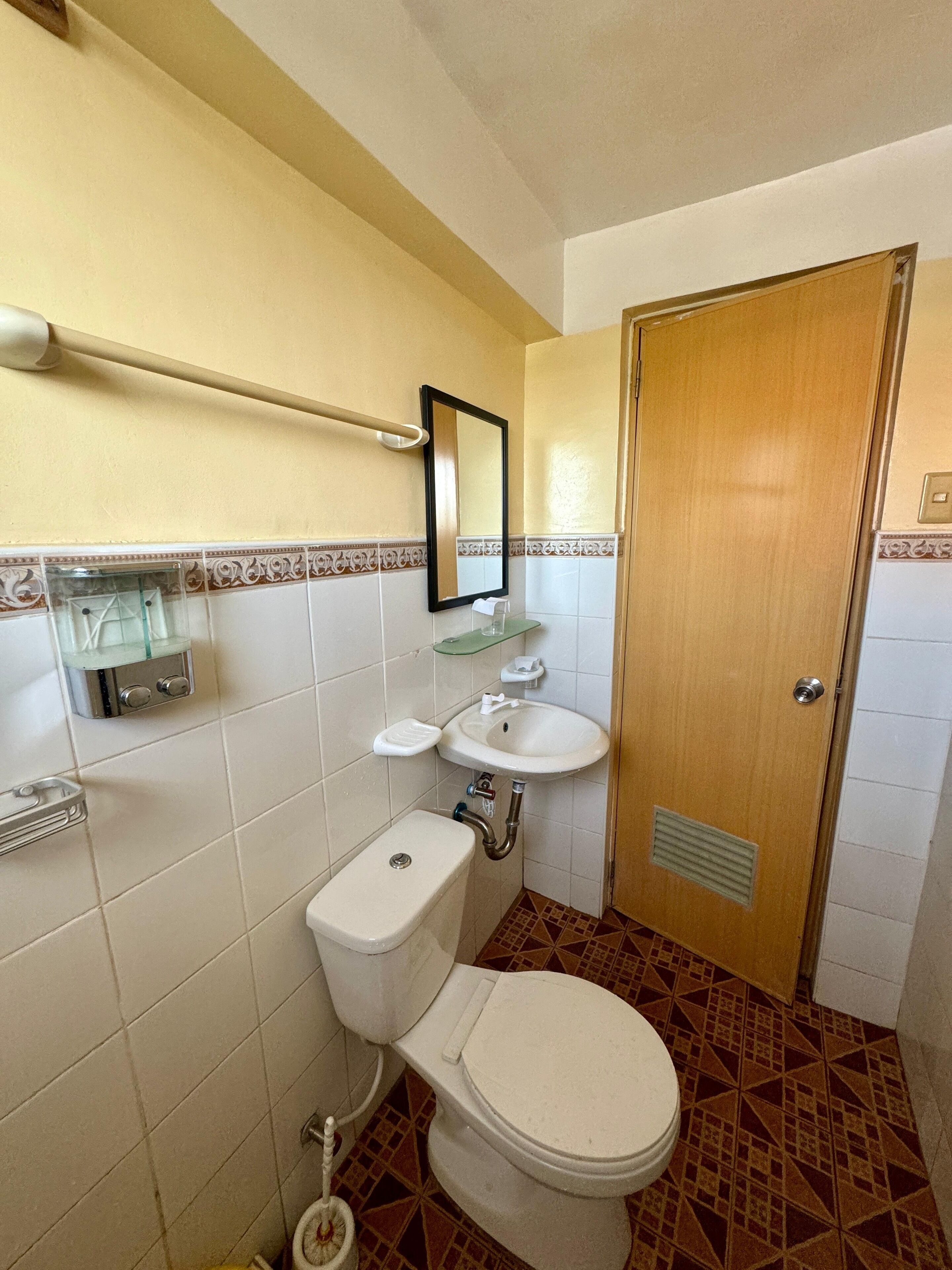 Ein Badezimmer mit Toilette, Waschbecken, Spiegel und einer Tür.
