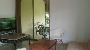 A living room with a sofa, a coffee table, a TV, and a dining area with chairs and a table. - Beautiful complete 2 bedroom apartment, Tulum Centro! Aluxe (Tulum)