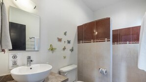 A bathroom with a white sink, toilet, and shower. There are butterfly wall decals and a towel hanging on the wall. - Beautiful complete 2 bedroom apartment, Tulum Centro! Aluxe (Tulum)