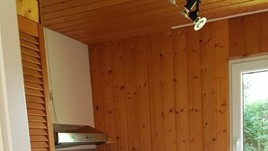 A compact kitchen with wooden walls, a built-in oven, a coffee maker, and a trash bin. - Quietly located bungalow with a view of the dam (Zeulenroda-Triebes)